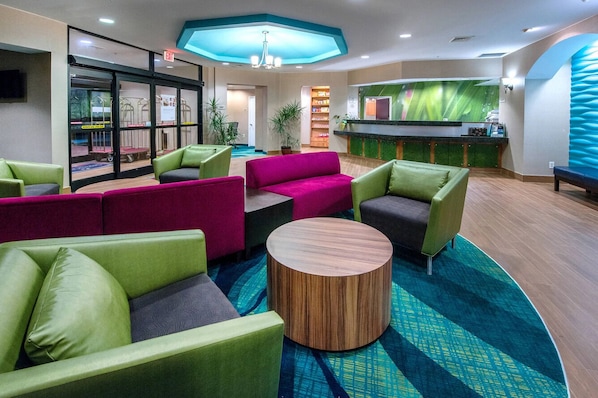 A lobby with green and pink seating, a reception desk, and a large window.
