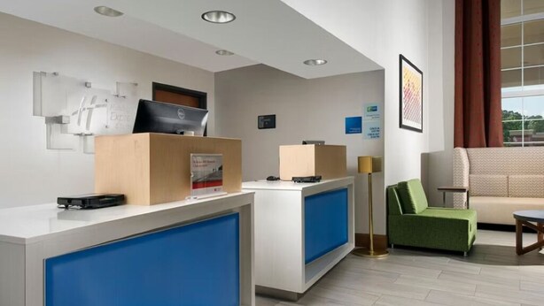 Ein Hotel-Empfangsbereich mit modernem Design, der einen Empfangstresen, ein grünes Sofa und ein großes Fenster mit Blick ins Freie umfasst.