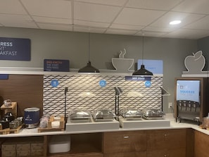 Un espace dédié au petit-déjeuner, avec des présentoirs clairement identifiés pour les œufs, les plats chauds et les jus de fruits.
