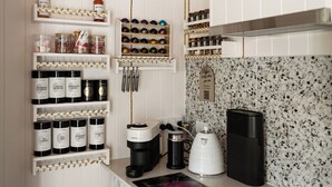 A kitchen with white cabinetry, a coffee machine, and various kitchen utensils.