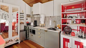 A modern kitchen with white cabinetry, a wooden ceiling, and a red telephone shelf.