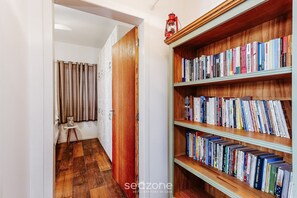Ein Korridor mit Holzboden, einem Bücherregal voller Bücher und einer Tür zu einem anderen Raum.