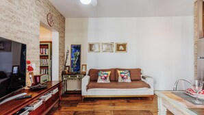 Una sala de estar con sofá blanco, piso de madera y estantería.