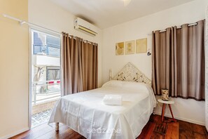 Ein Hotelzimmer mit einem Bett, Vorhängen, einem kleinen Tisch mit Lampe und Bildern an der Wand.