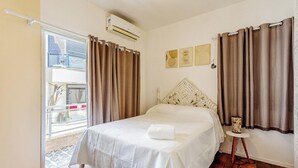Un dormitorio con cama, cortinas, una ventana y una obra de arte en la pared.