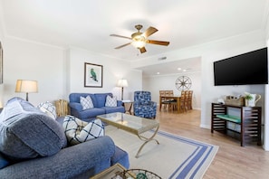 A living room with a sofa, coffee table, and a ceiling fan. - Pal's Palmetto Place - 3BR Bungalow w/ Ocean Views (North Myrtle Beach)