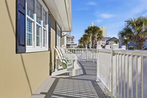 A coastal building with a balcony, white railings, and a view of the sea and other buildings. - Pal's Palmetto Place - 3BR Bungalow w/ Ocean Views (North Myrtle Beach)