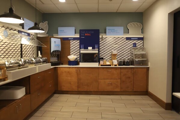 A modern kitchen with wooden cabinets, a fruit section, and a bakery display.
