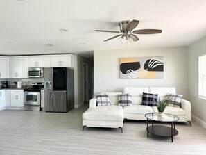 A modern kitchen with white cabinets, stainless steel appliances, and a ceiling fan. - Home close to Clearwater beach (Largo)
