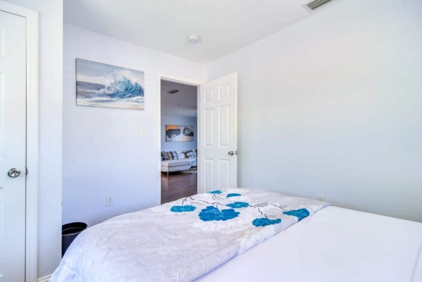 A bedroom with a bed, a door, and a hallway leading to another room.