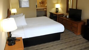 A hotel room with a bed, bedside lamps, a desk with a computer, a television, a mirror, and a bathroom visible in the background. - Affordable Stay Near Liberty University with Free Breakfast & Outdoor Pool (Lynchburg)