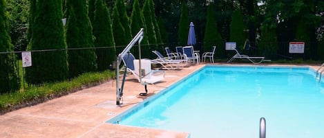 Una piscina con sillones de descanso y un letrero de seguridad.