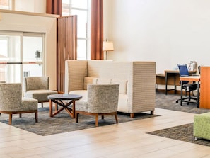 Un vestíbulo de hotel con zona de estar, un mostrador de recepción y una ventana.