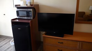 Ein Hotelzimmer mit einer Mikrowelle, einem Fernseher auf einer Holzkommode und einem Mülleimer.