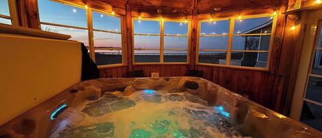 Un bain à remous avec un intérieur en bois et des fenêtres donnant sur un paysage.