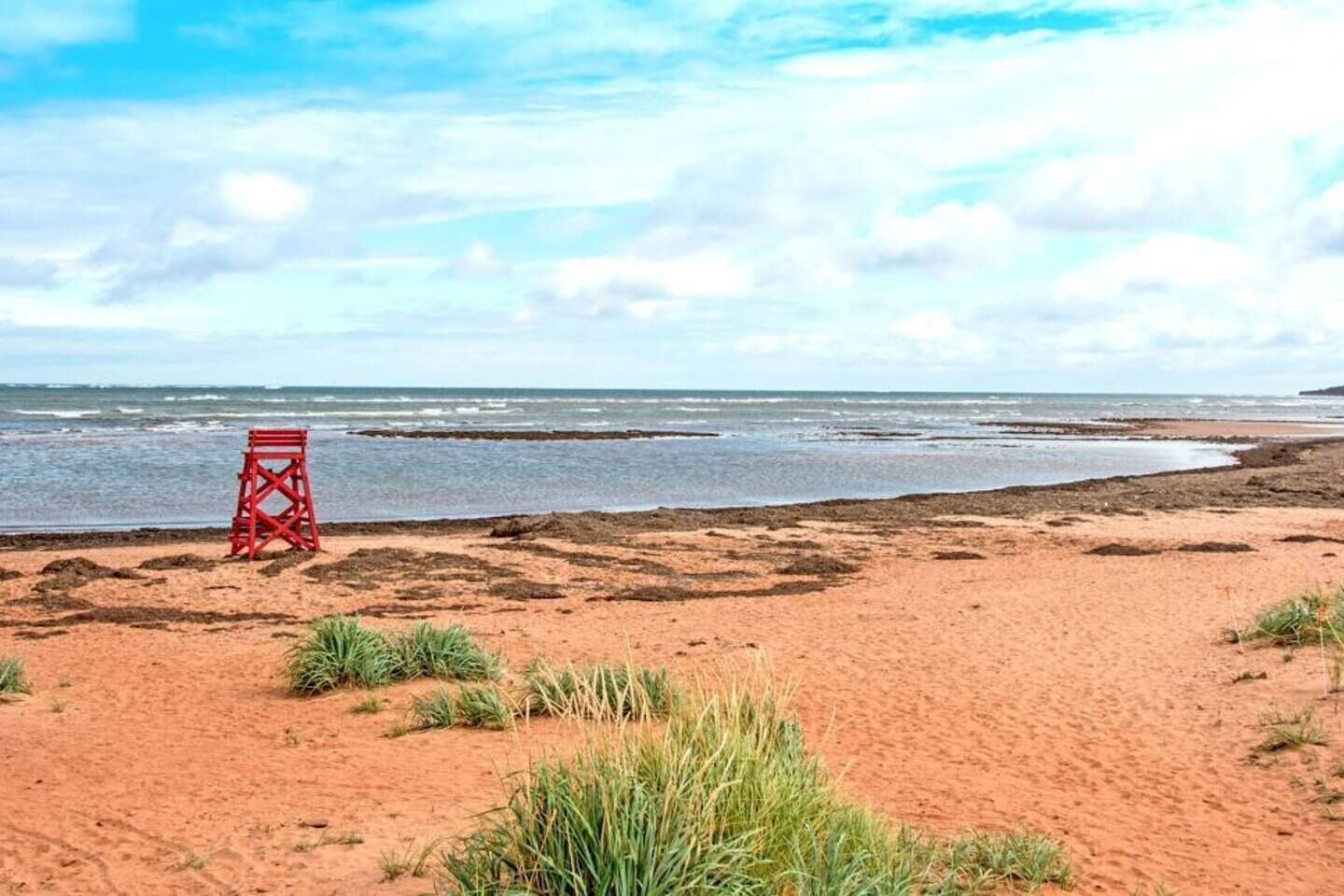 Une plage avec une tour de surveillance pour les sauveteurs, un sol sablonneux et une vue sur l’océan.