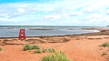 Une plage avec une tour de surveillance pour les sauveteurs, un sol sablonneux et une vue sur l’océan.