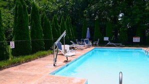 Una piscina con sillones de descanso y un letrero de seguridad.
