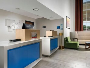 Ein Hotel-Empfangsbereich mit modernem Design, inklusive einer Rezeption, einem grünen Sofa und einem großen Fenster mit Blick.