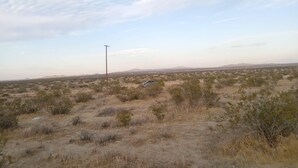 Paisaje desértico con vegetación escasa, un poste de electricidad y un vehículo.