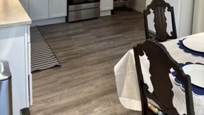 Cocina compacta con gabinetes blancos, horno de acero inoxidable, microondas y refrigerador.