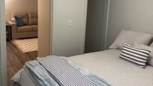 Un dormitorio con cama, una puerta y un pasillo que conduce a otra habitación.