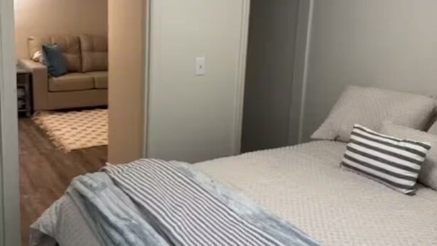 A bedroom with a bed, a door, and a hallway leading to another room. - Clay Street Retreat Entire home in Clinton, Illinois (Clinton)
