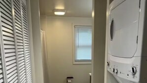 Una sala de lavandería con lavadora, inodoro y ventana.