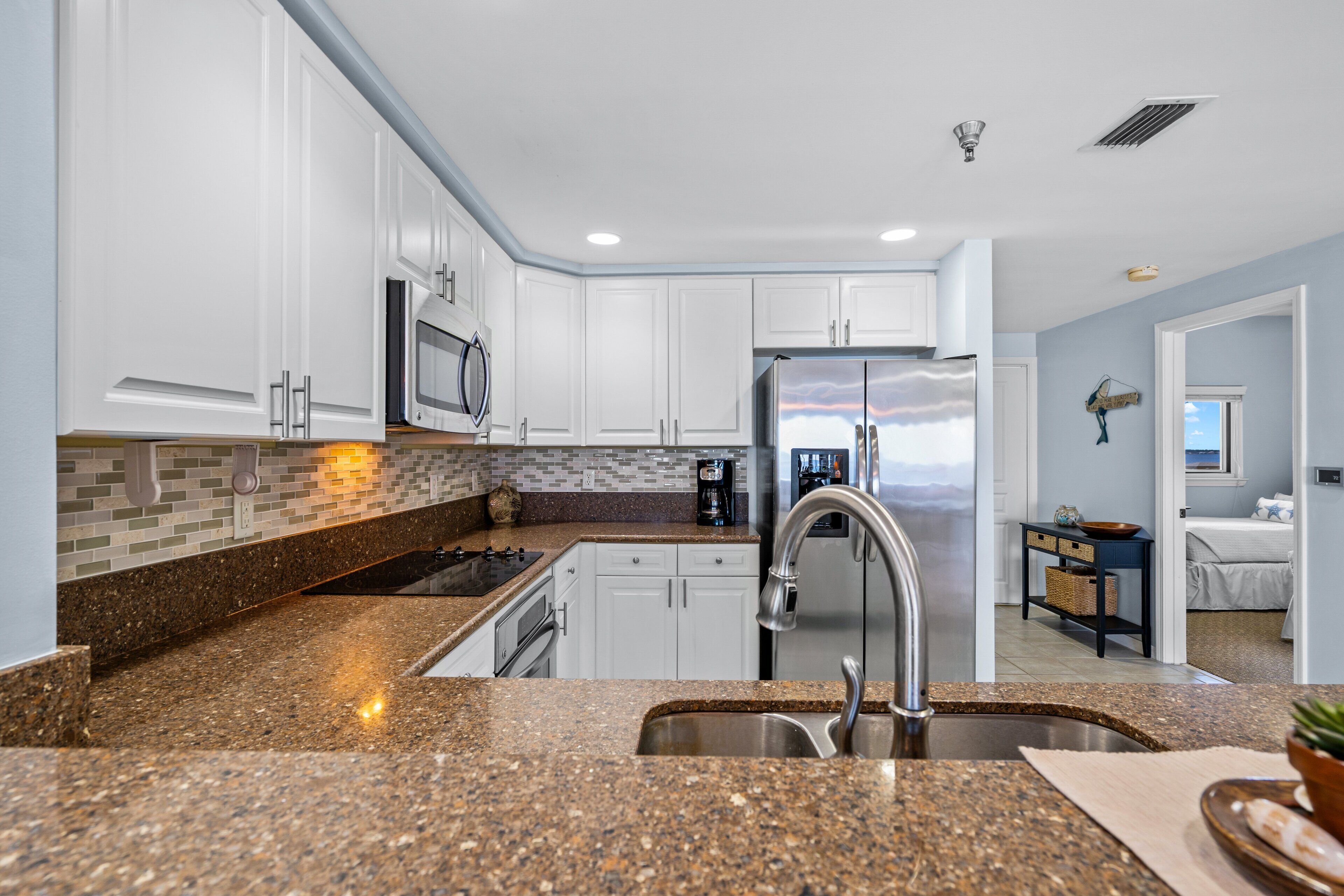 A modern kitchen with granite countertops, stainless steel appliances, and white cabinetry.