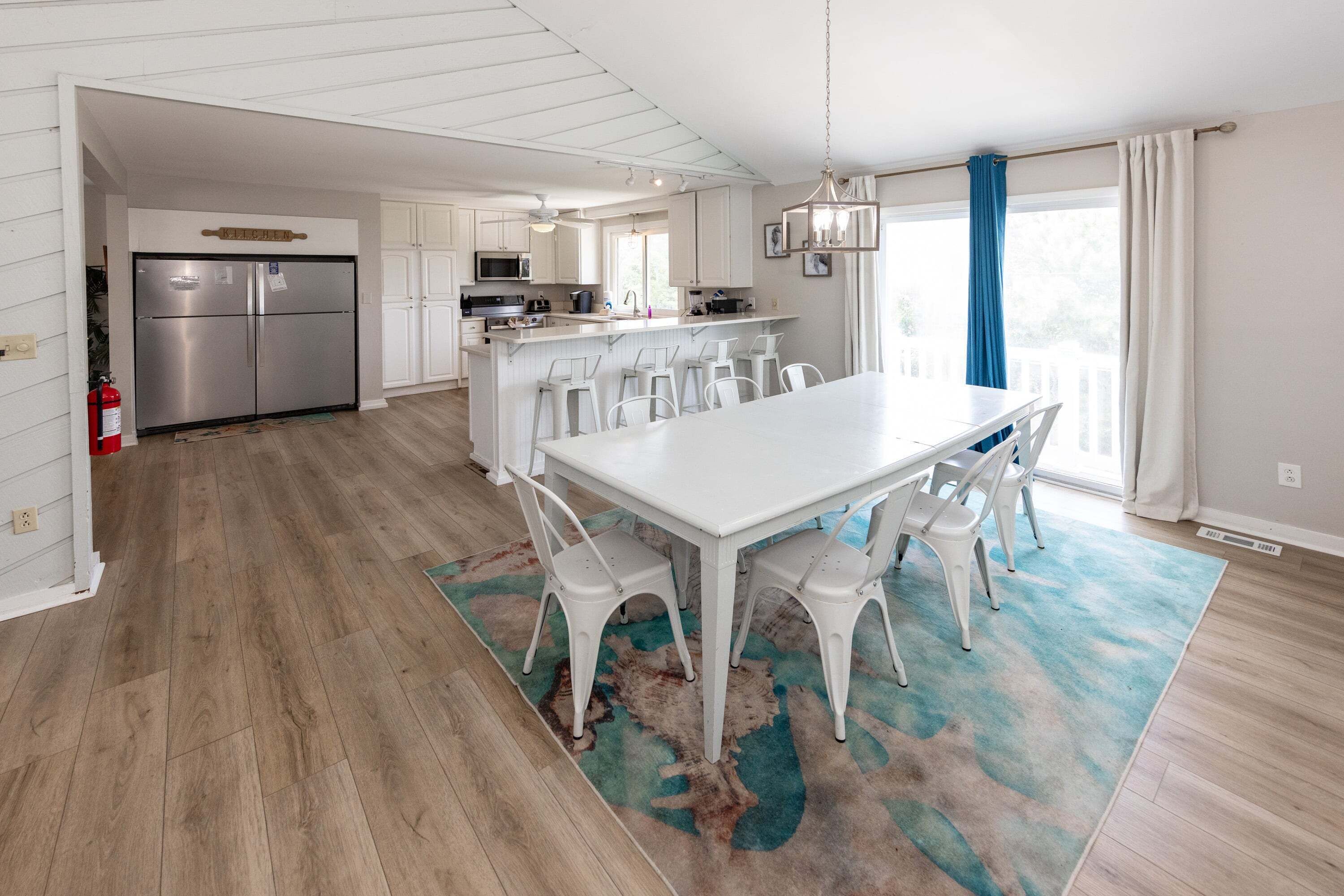 Une cuisine moderne avec des meubles blancs, des appareils en acier inoxydable et un îlot central doté de tabourets de bar.