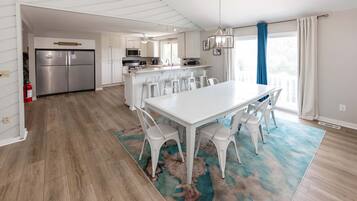 Een moderne keuken met witte kastjes, roestvrijstalen apparatuur en een centraal kookeiland met barstoelen.
