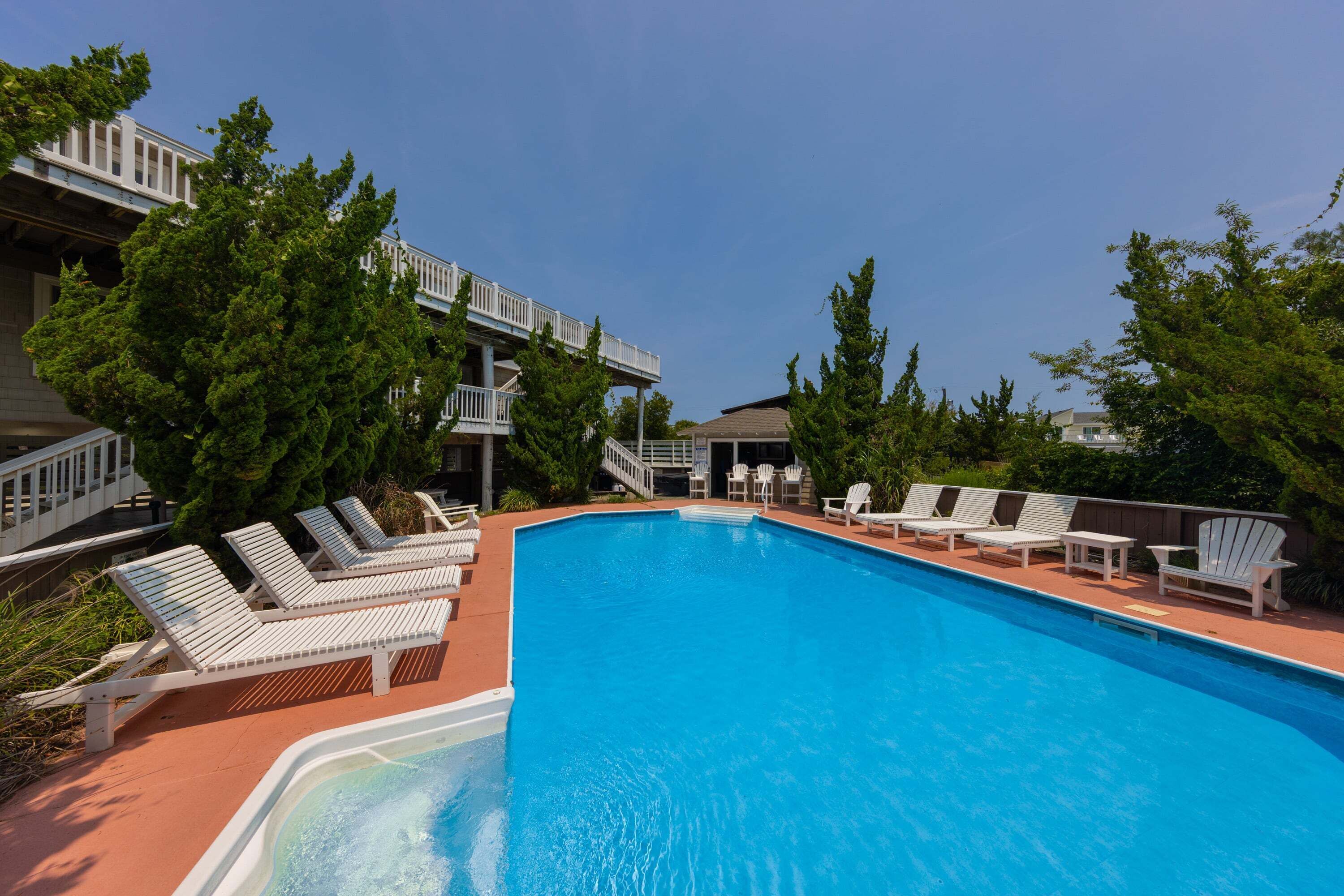 Une piscine avec des chaises longues et une allée couverte.