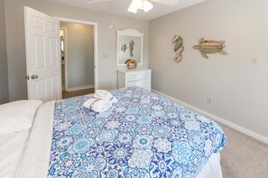 A bedroom with a bed, a dresser, a mirror, and decorative wall art.