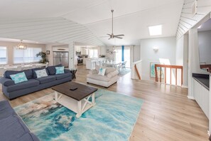 A spacious living area with a sofa, coffee table, and a dining area with chairs. - 9BR Sandbridge beach home with pool, hot tub, and game room (Virginia Beach)