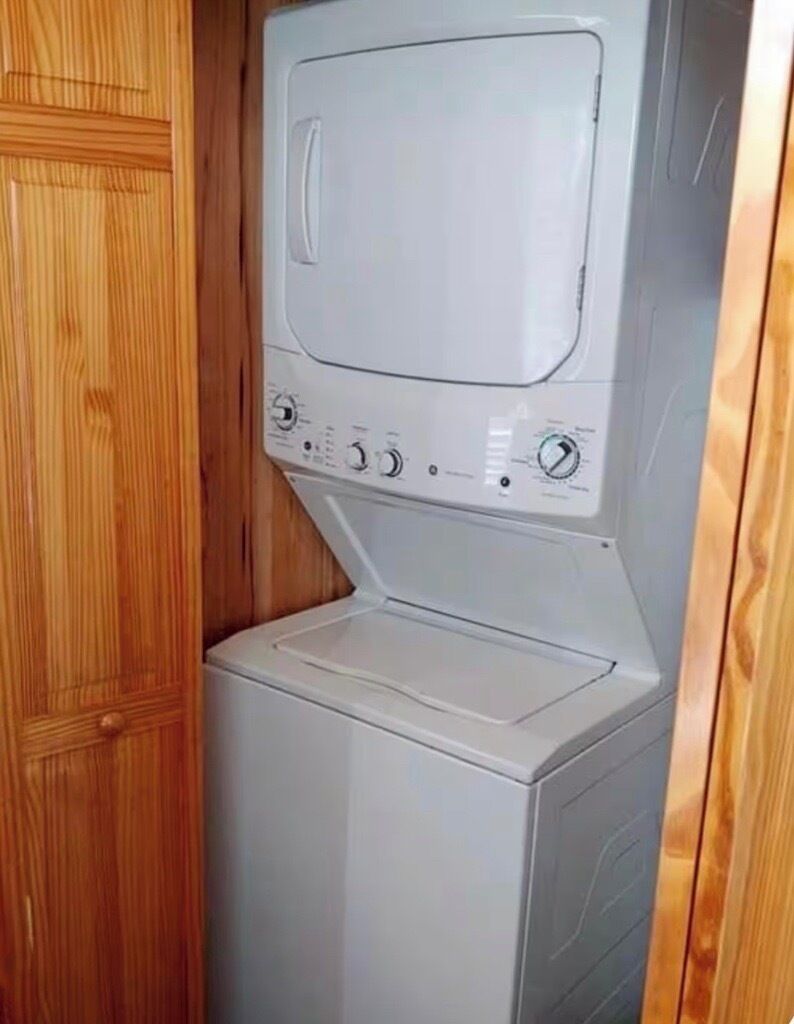 Un appareil combiné lave-linge et sèche-linge, de dimensions réduites, installé dans un meuble en bois.