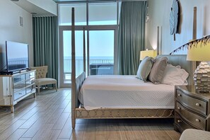 A hotel room with a bed, a television, a desk, and a chair. - Turquoise Place D2201 | Balcony Hot Tub & Grill (Orange Beach)