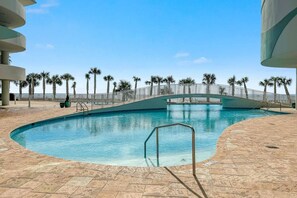 A swimming pool with a bridge, surrounded by palm trees and a clear sky. - Turquoise Place D2201 | Balcony Hot Tub & Grill (Orange Beach)