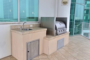 A compact outdoor kitchen with a sink, a grill, and a cabinet. - Turquoise Place D2201 | Pools, Lazy River + Balcony Hot Tub & Grill (Orange Beach)