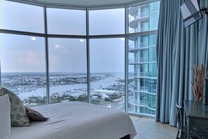 A bedroom with a large window, a bed, and a view of a cityscape and water. - Turquoise Place D2201 | Pools, Lazy River + Balcony Hot Tub & Grill (Orange Beach)