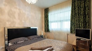 A bedroom with a bed, a TV, a dresser, and a window with curtains. - Sia Mountain Apartment (Predeal)