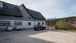 A building with a sloped roof, a parked car, and a gravel driveway. - Sia Mountain Apartment (Predeal)