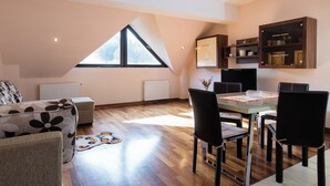 A modern loft with a dining area, a sofa, and a large window. - Sia Mountain Apartment (Predeal)