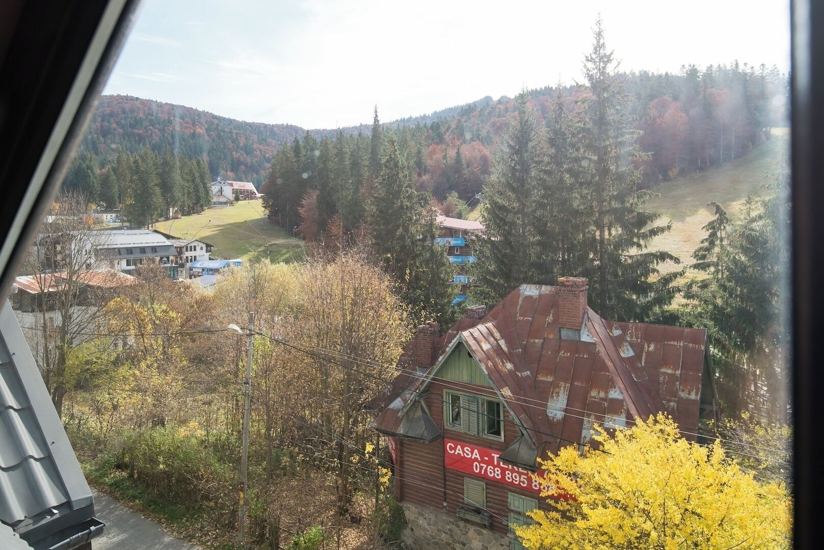 A rural landscape with a red-roofed building labeled 'CASA - TIN' and a view of a valley with trees and a distant house.