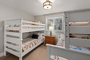 A room with bunk beds, a window with a view, and a bedside table with a lamp. - 3BR West Vail riverfront duplex, hot tub, fireplace, yard (Vail)