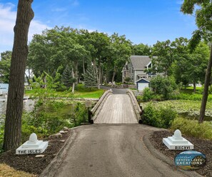A private property with a wooden bridge leading to a house surrounded by trees.