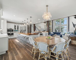 A modern kitchen with white cabinetry, stainless steel appliances, and a central island with bar stools.