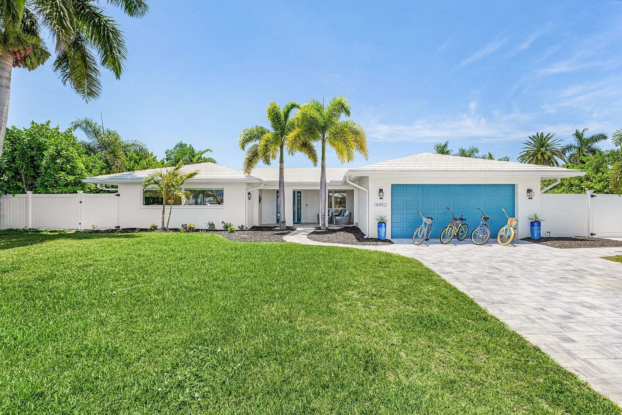 A modern two-story house with a garage, a well-maintained lawn, and a clear sky.