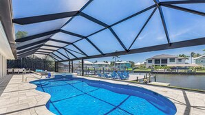 Une piscine dotée d’un espace couvert, de chaises longues et offrant une vue sur un quartier résidentiel.
