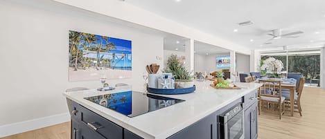 Cocina moderna con una isla grande, electrodomésticos integrados y un comedor con vistas.
