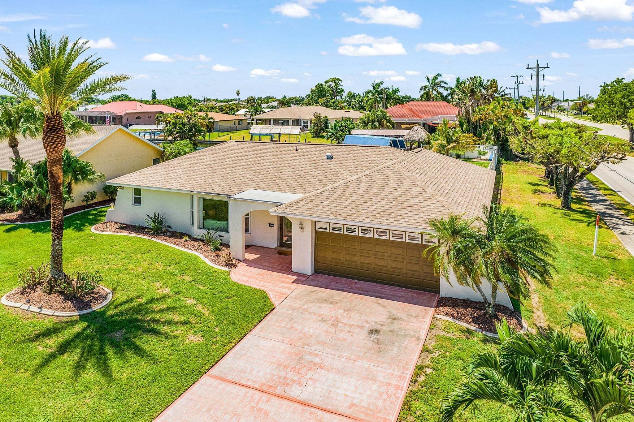 A residential house with a tiled roof, a garage, and a front yard with a palm tree.